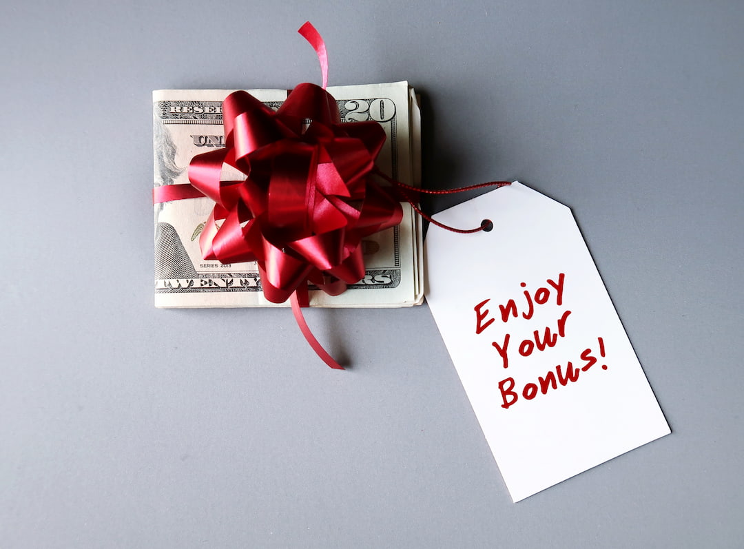 Cash bonus with red ribbon attached answering how much are Christmas bonuses taxed